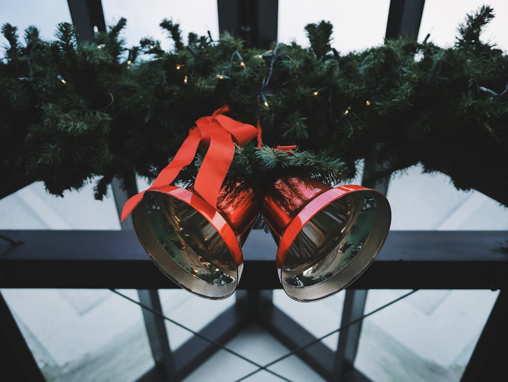 two red steel bells beside green Christmas decoration