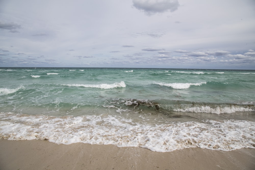 sea waves crashing on shore during daytime