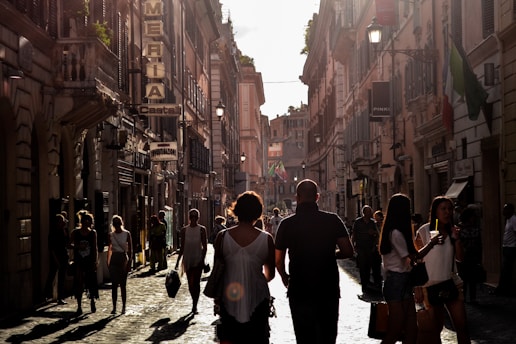 A vibrant street scene with people engaging in conversation and prayer, illuminated by warm orange and red tones.