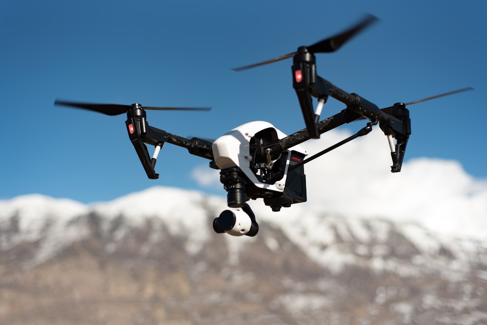 Weißer und schwarzer Quadrocopter schwebt unter blauem Himmel