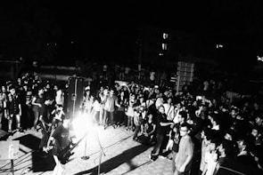 Wide shot of a lively outdoor concert with a diverse crowd enjoying rhythmic percussion beats