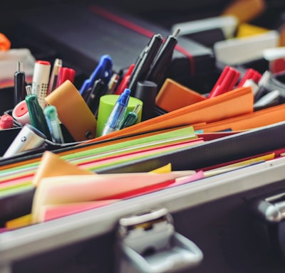 assorted pen and colored papers in organizer case