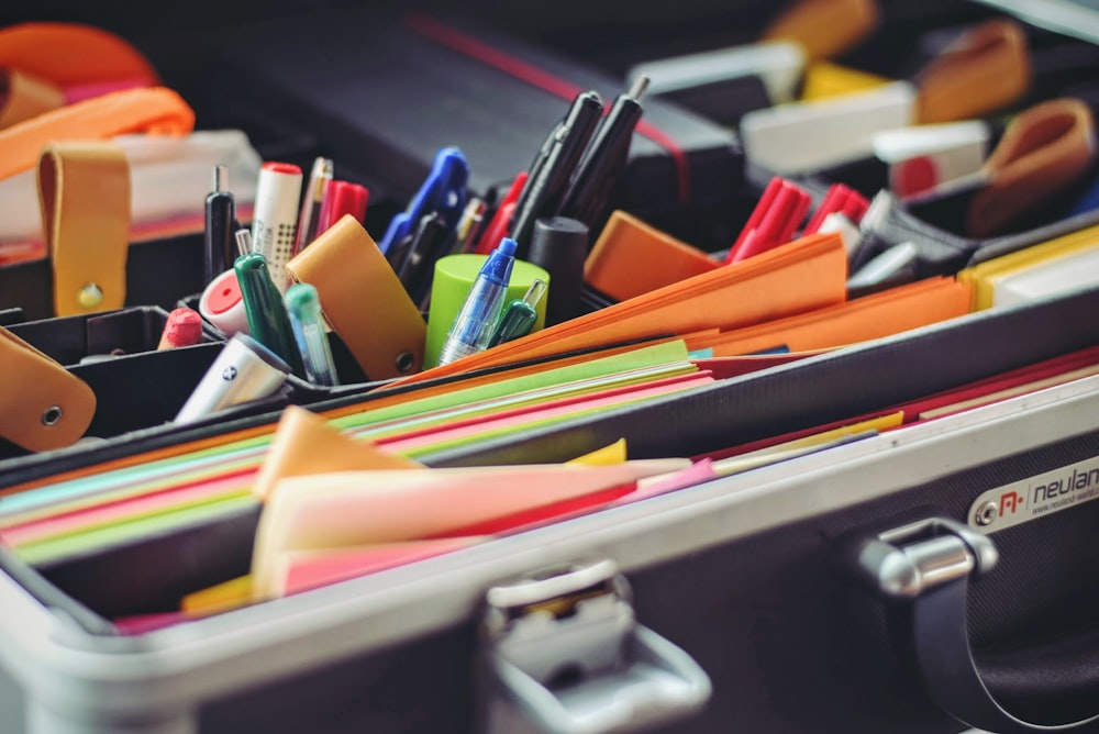 assorted pen and colored papers in organizer case