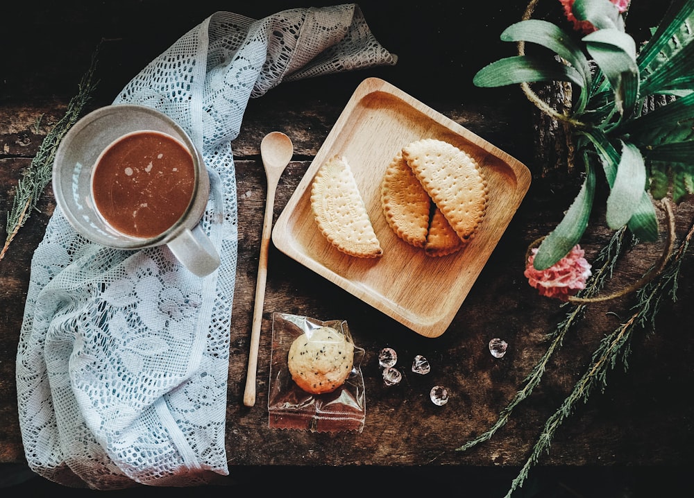 Fotografía plana de pastelería en bandeja junto a taza de vidrio