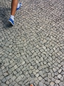 A close-up of feet walking on a sidewalk, avoiding obstacles.