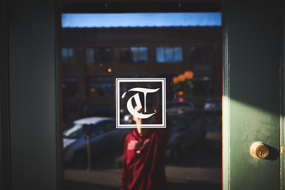 Persona in camicia rossa nel riflesso della finestra della porta con serratura e logo