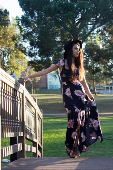 A stylish woman wearing a flowing dress in a sunlit park.