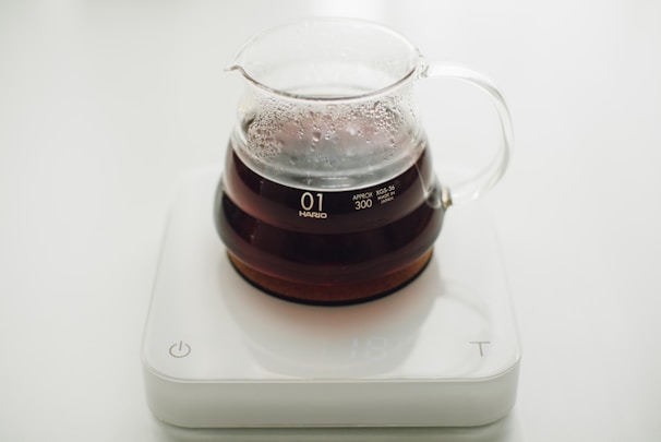 Sleek, clear glass carafes with minimalist matte black lids, placed on a smooth white countertop.
