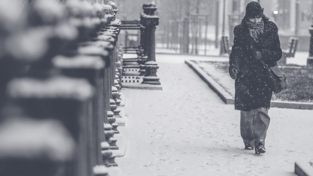 grayscale photo of person walking on street, Budapest in the snow