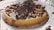 A delicious waffle topped with whipped cream, chocolate sauce, and chocolate shavings, served on a white plate with scattered chocolate droplets around it.
