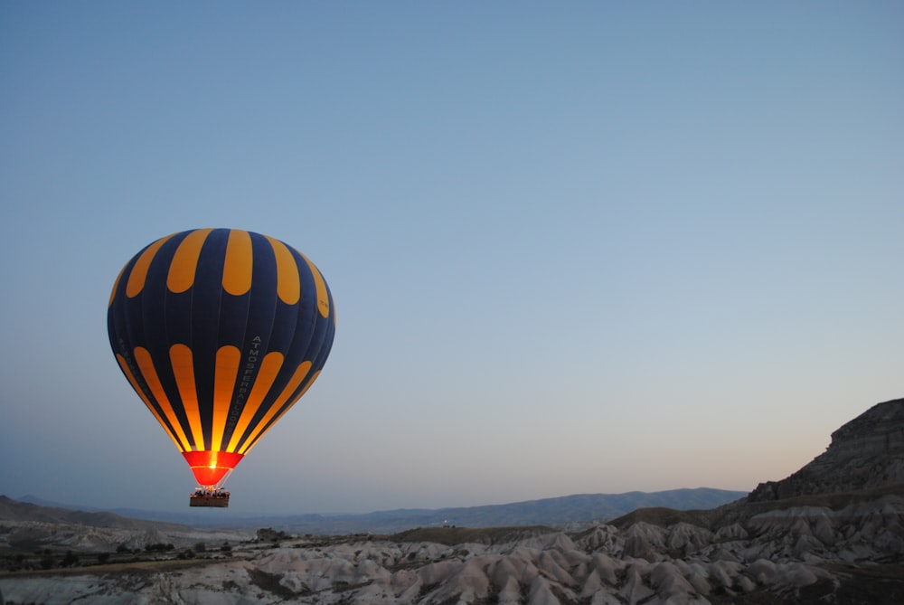 blue and yellow hot air balloon at top of high rise mountains