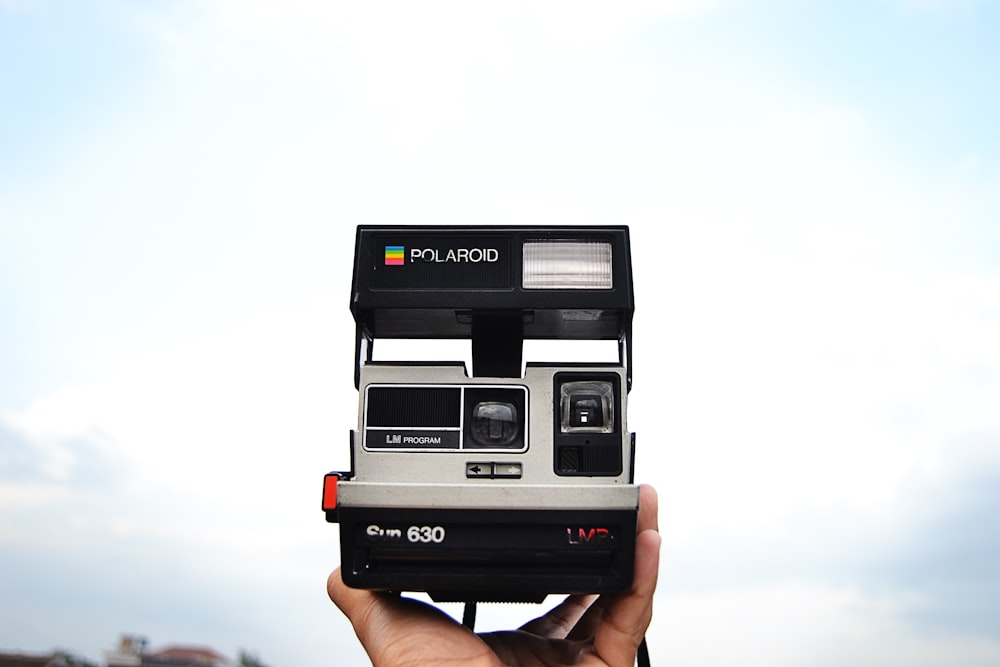 person holding black and gray Polaroid 630 instant camera