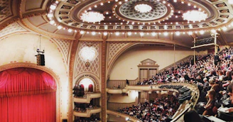 Audience applauding in an elegant opera house filled with warm lighting.
