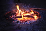 Close-up of a fire pit glowing warmly with logs arranged for a cozy evening.