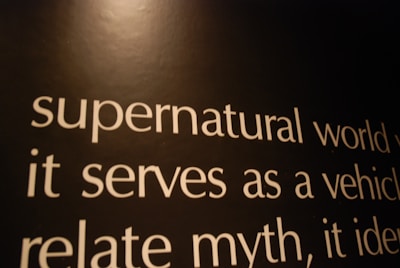 Text in white font is displayed on a dark background. The words include 'supernatural world', 'it serves as a vehicle', and 'relate myth'. The lighting casts a warm tone across the image, giving the text an expressive look.