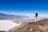 A happy traveler standing on the vast white salt flats of Salar de Uyuni under a clear blue sky.