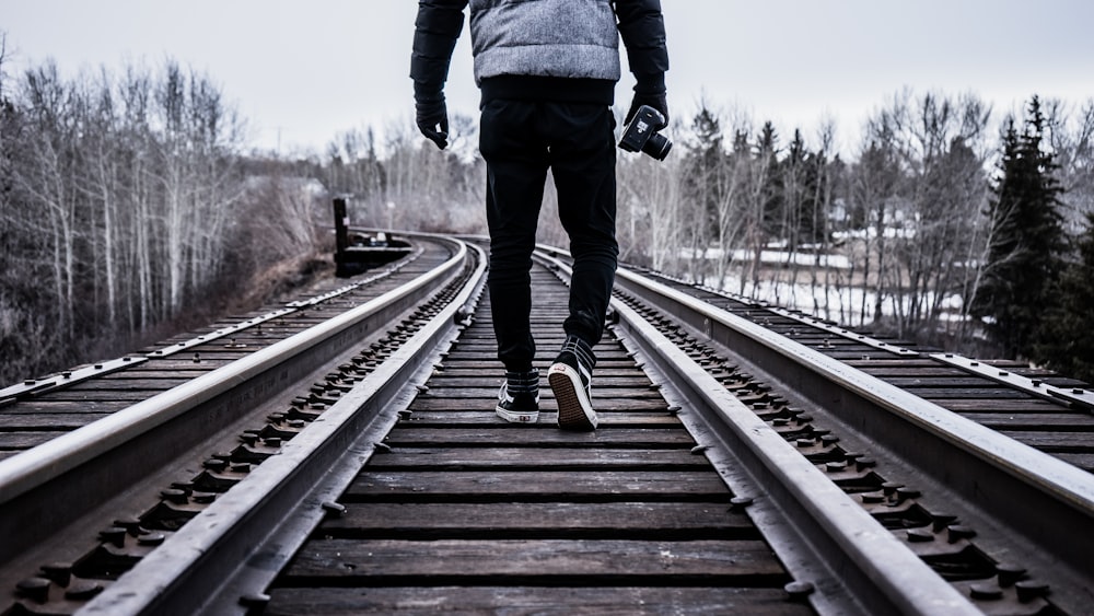 man waking on train rail