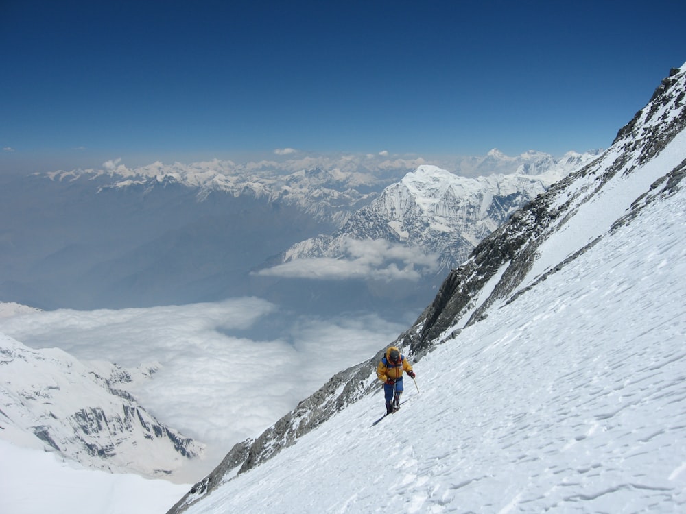 person climbing snow-covered mountain during daytime