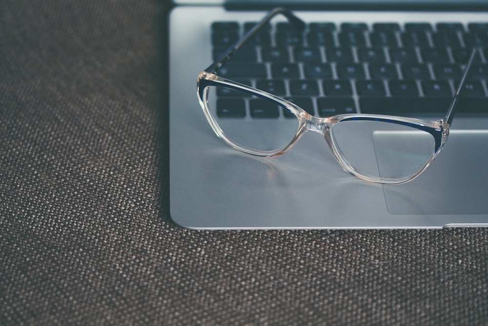 durchsichtige Brille mit schwarzem Rahmen am Laptop