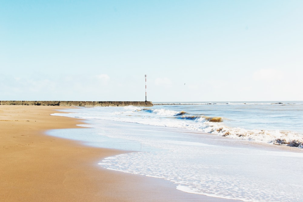 Playa de arena marrón y olas del mar durante el día