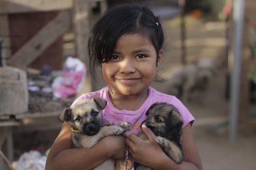 Smiling children petting a rescued puppy during a community event.