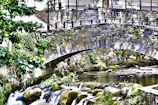 A small stream crossing a moss-covered stone bridge on a hiking route