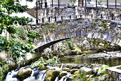 A small stream crossing a moss-covered stone bridge on a hiking route
