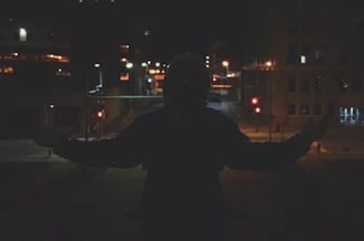 Nighttime city backdrop with a figure in a black nisqala jacket, illuminated by muted street lamps