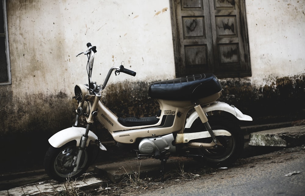 grey moped motorcycle park near wall