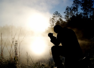 silhouette of kneeling man praying