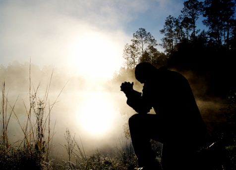 silhouette of kneeling man praying