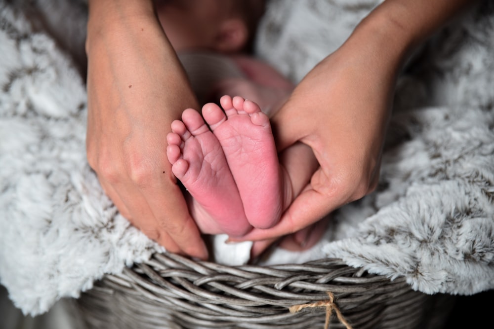Persona sosteniendo los pies del bebé