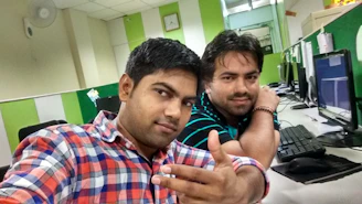 Brothers smiling while reviewing documents side by side in a clean office.