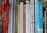 A collection of books tightly packed on a shelf, featuring titles on topics like narrative research, personal stories, and human sciences. Some books are in English, while others are in Finnish. The spines are various widths and colors, and some books have ribbons hanging out.