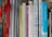 A collection of books tightly packed on a shelf, featuring titles on topics like narrative research, personal stories, and human sciences. Some books are in English, while others are in Finnish. The spines are various widths and colors, and some books have ribbons hanging out.