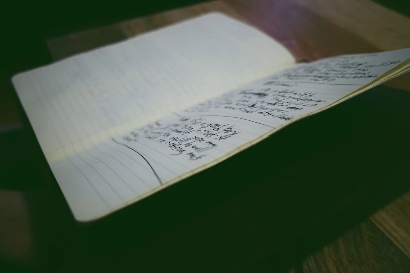 A warmly lit room with an open Bible and a notebook filled with handwritten notes.