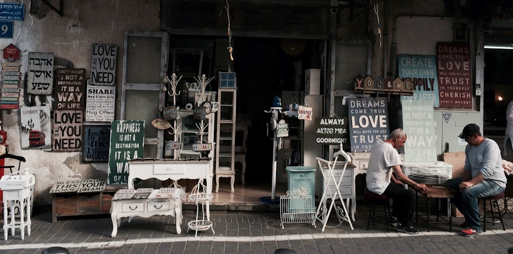 two men sitting in front of table beside assorted wall decors store