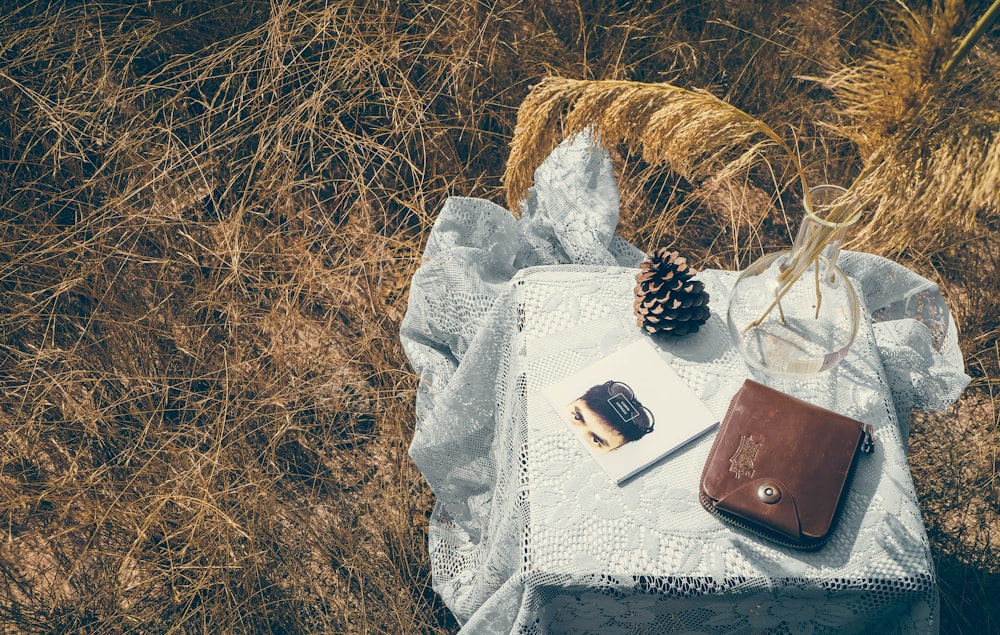 bag, vase, and conifer cone on table covered in white mantle