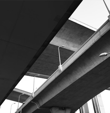 Multiple layers of intersecting concrete bridges form a complex structure against the sky. Streetlights are attached along the edges, adding to the urban aesthetic.