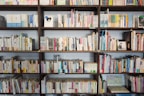 assorted books on brown wooden shelf at daytime