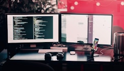 two black computer monitors on black table