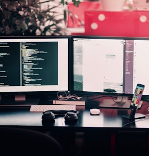 two black computer monitors on black table