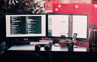 two black computer monitors on black table