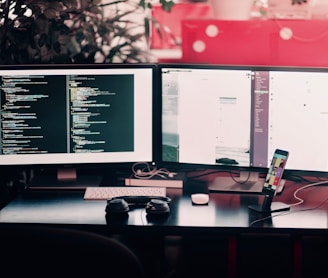 two black computer monitors on black table