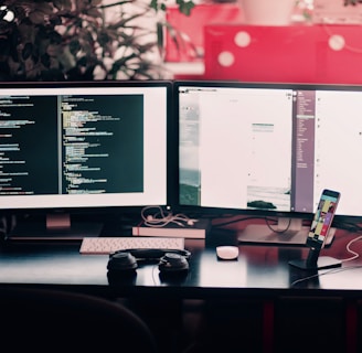 two black computer monitors on black table