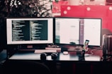 two black computer monitors on black table