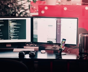 two black computer monitors on black table