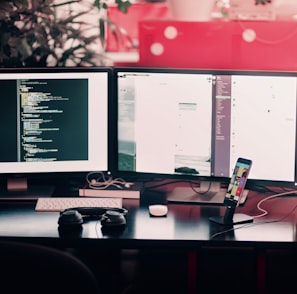 two black computer monitors on black table