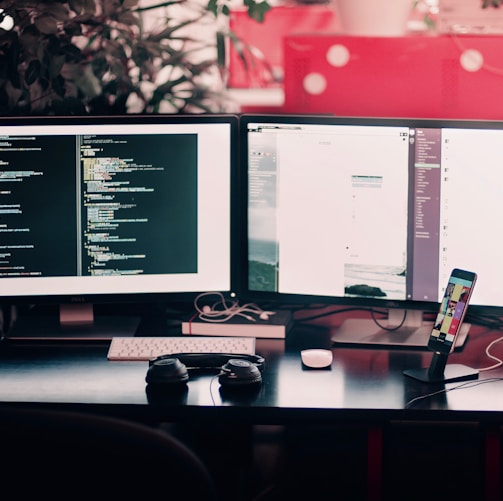 two black computer monitors on black table