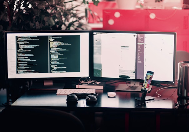 two black computer monitors on black table